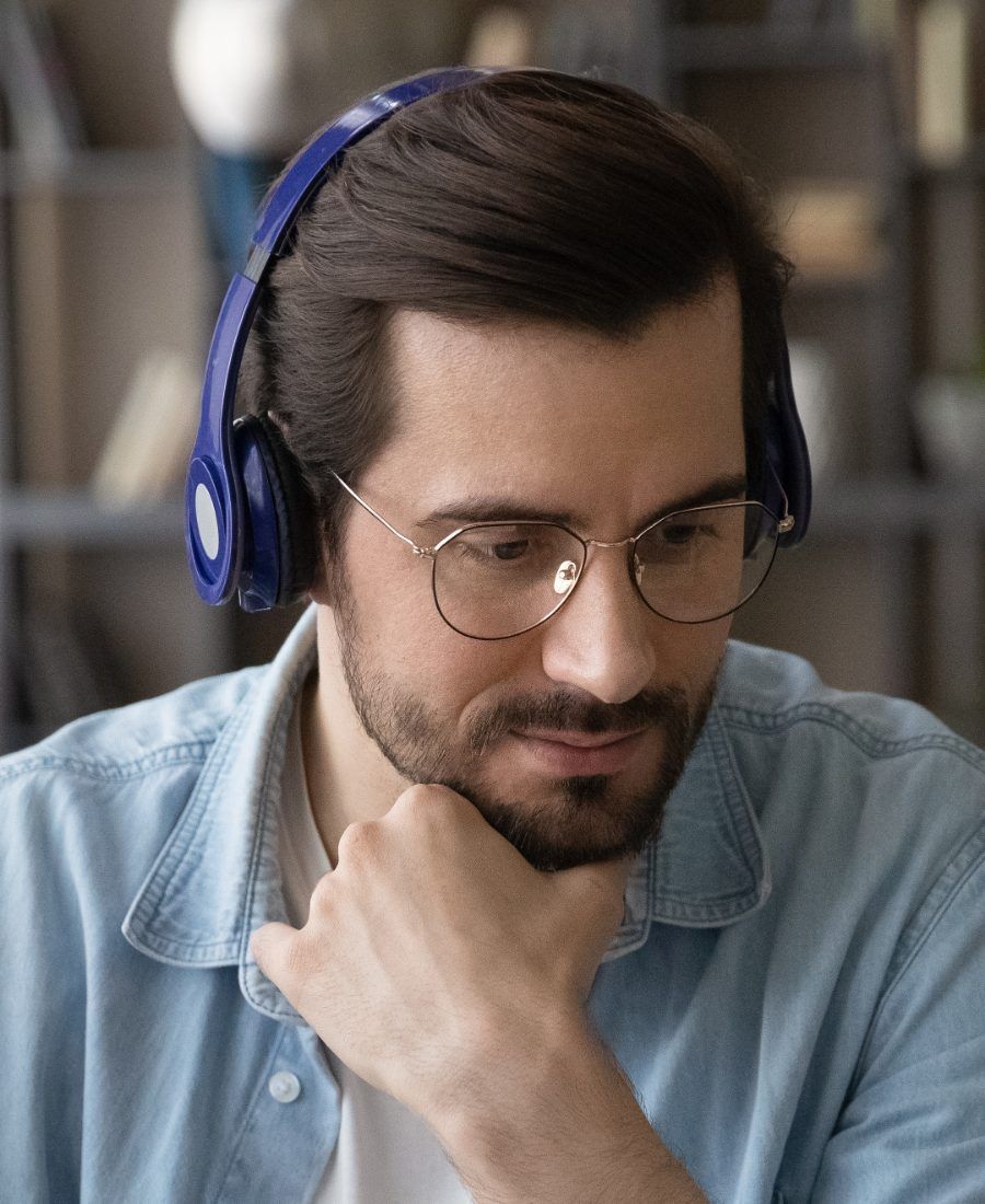 Teilnehmer im Live-Online-Unterricht am Schreibtisch, mit Kopfhörern, den Blick auf den Laptop gerichtet.
